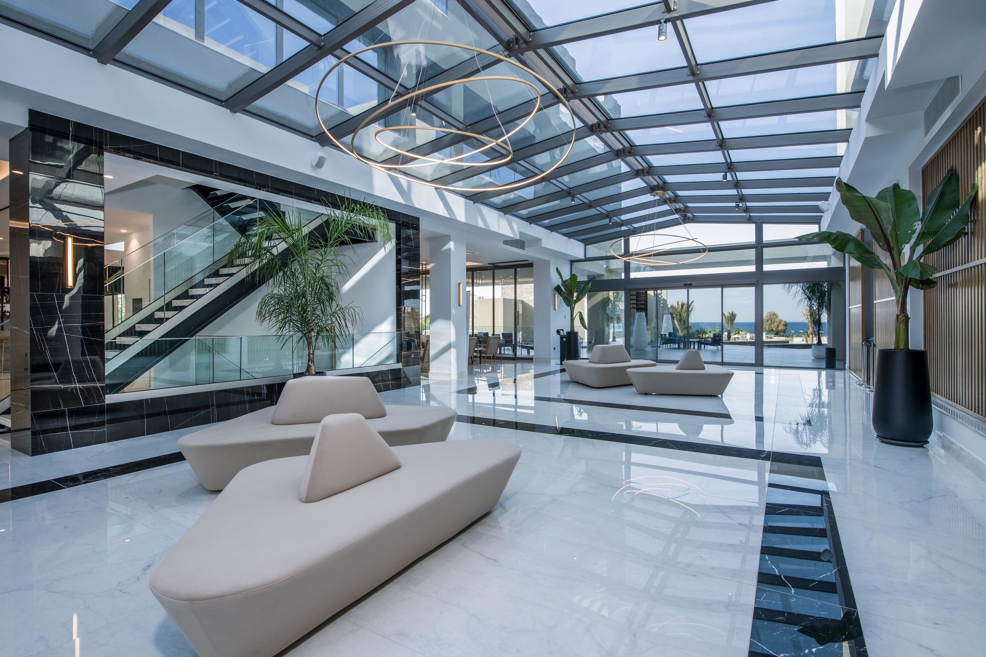 A spacious lobby with a glass ceiling, modern seating, and a staircase.