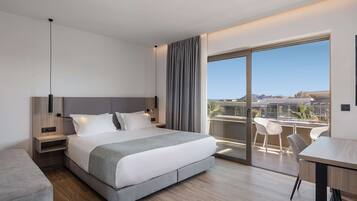 A modern hotel room with a large bed, bedside tables, a desk, and a balcony with a view.