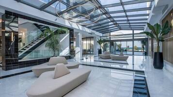 A spacious lobby with a glass ceiling, a staircase, and seating areas.