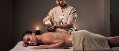 A massage therapy session in a dimly lit room with candles, a massage table, and a towel.