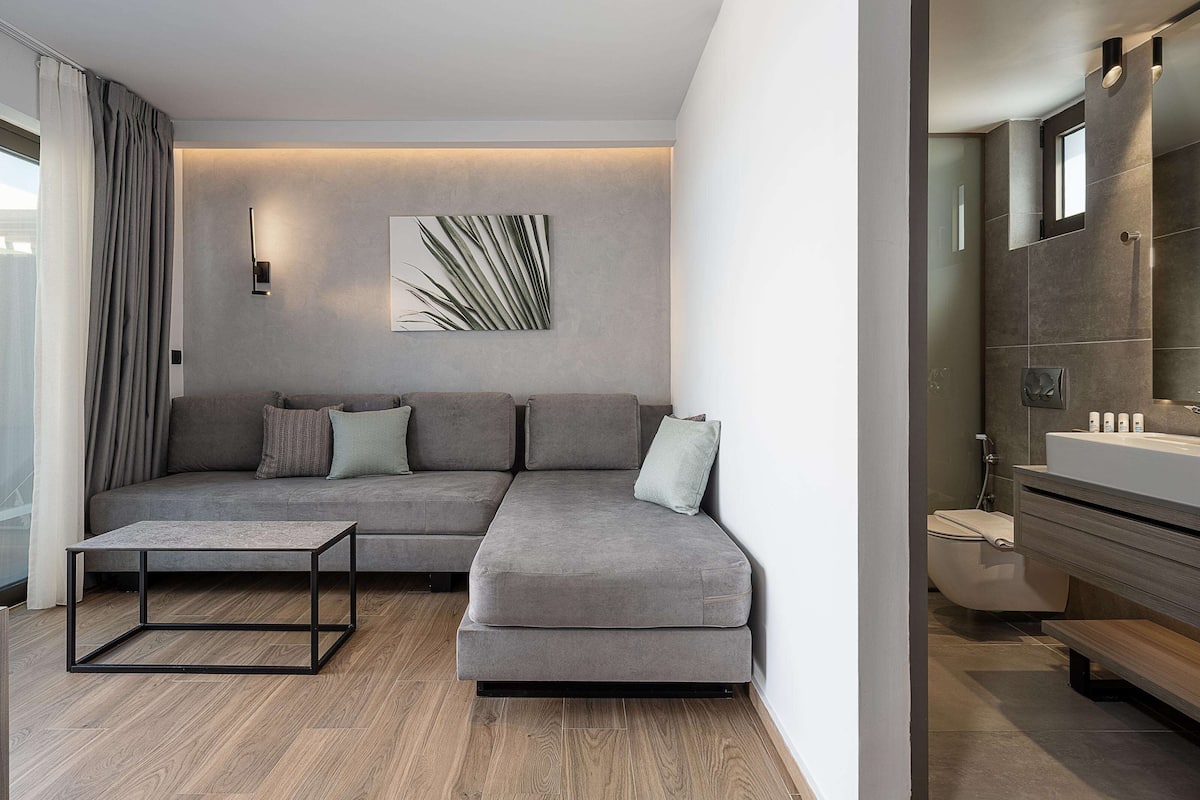 A modern living room with a grey sectional sofa, a coffee table, and a wall-mounted light fixture.