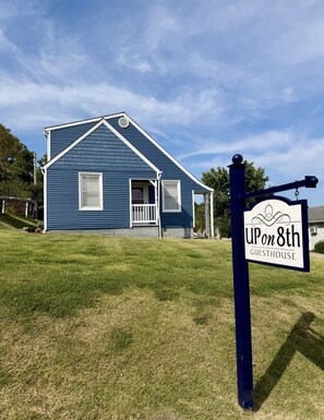 A blue house with a porch and a sign that reads 'UPon8th GUESTHOUSE'. - Newly remodeled home in Historic Hermann Wine Counrtry. (Hermann)