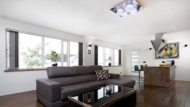 Ein modernes Wohnzimmer mit einem großen Ecksofa, einem Glastisch und einer Küchenzeile mit einer Marmorinsel.