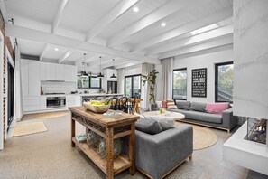 A modern living room with a grey sofa, a wooden coffee table, and a dining area with a white table and chairs. - Sorrento Beach House (Sorrento)