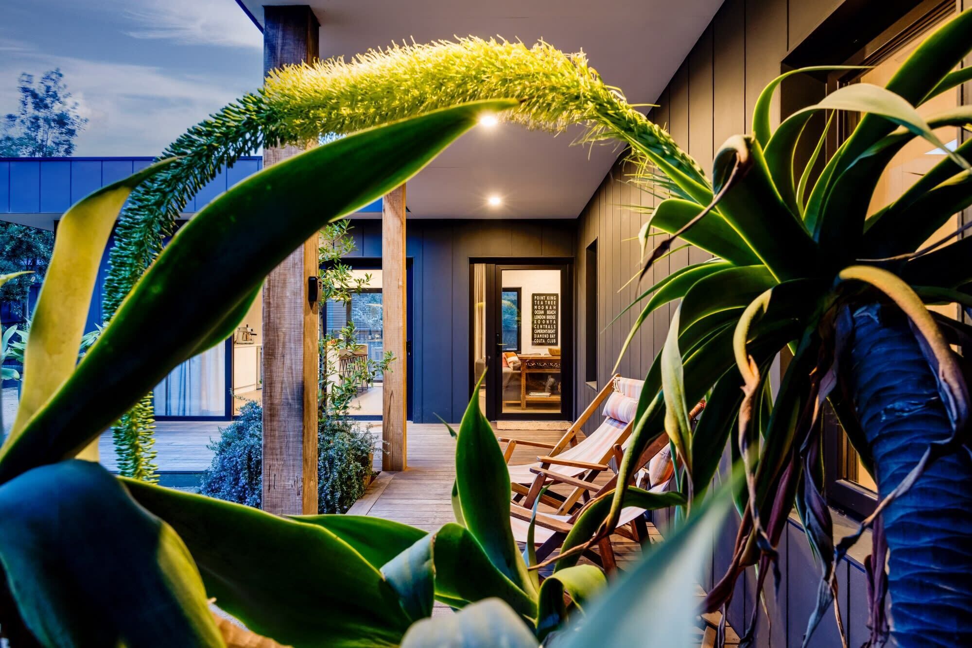 Un intérieur moderne avec une terrasse en bois, des chaises longues et une vue sur l’océan.