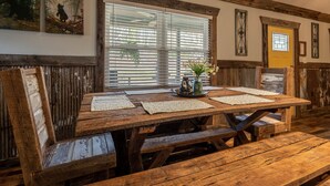 Una mesa de madera rústica con bancos, rodeada de paneles de madera y obras de arte.
