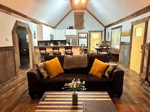 A cozy living room with a dark sofa, wooden coffee table, and a vase of flowers. - Charming Cabin + Hot Tub ~ Lake James & Linville Gorge ~ Pet-Friendly + Wi-Fi! (Morganton)