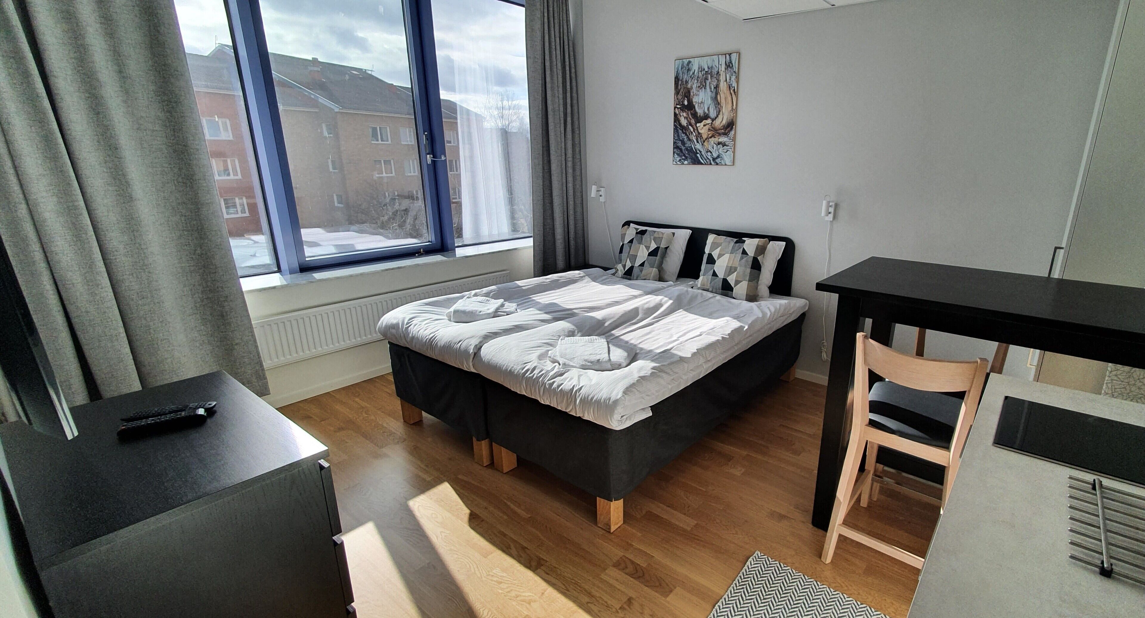 A modern bedroom with a large bed, a desk, and a chair.