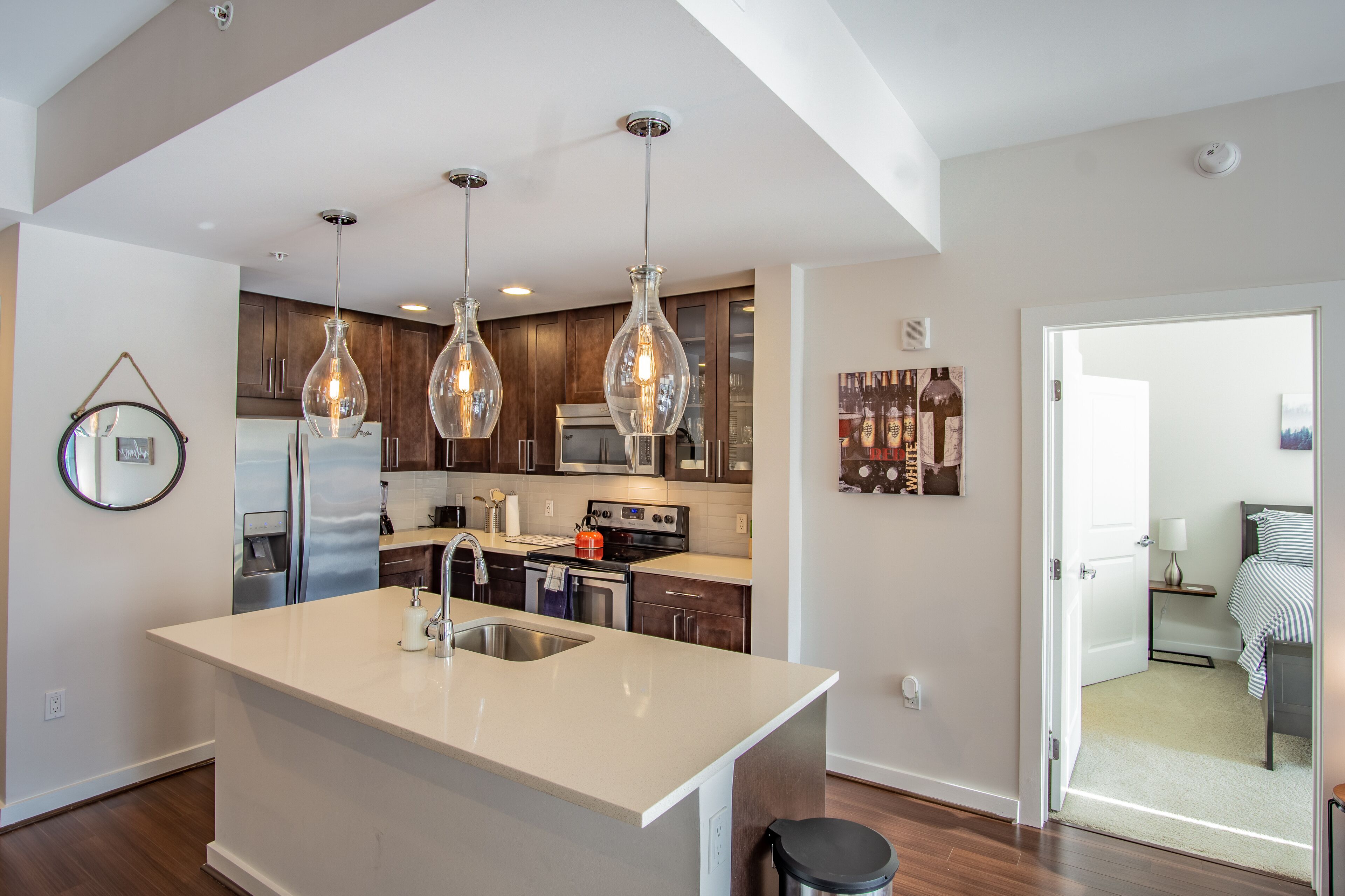 A modern kitchen with a central island, stainless steel appliances, and pendant lighting.