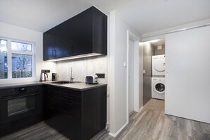 Een moderne keuken met zwarte kastjes, een ingebouwde oven en een raam.