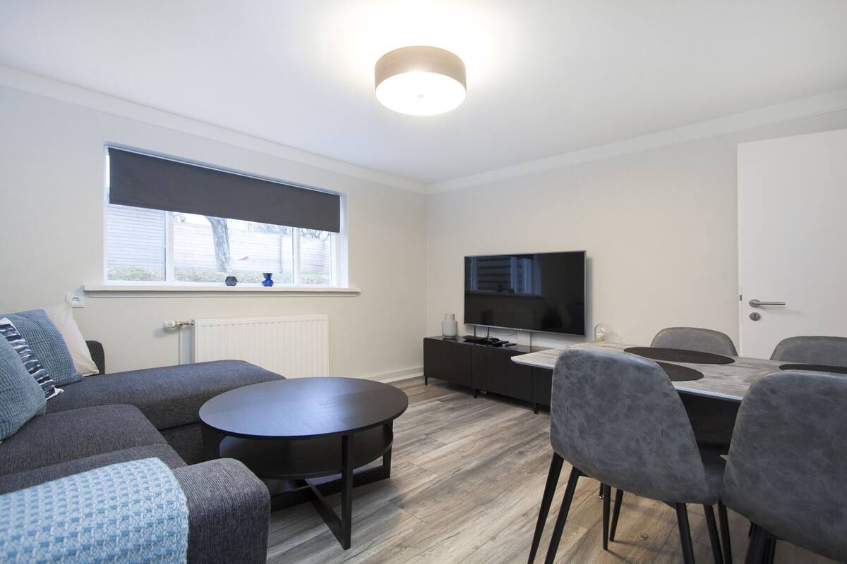 A modern living room with a sofa, a round table, and a TV.