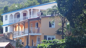 Un edificio a più piani con balconi, situato vicino a una costa rocciosa e acque cristalline.