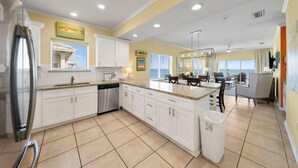 Una cocina amplia con armarios blancos, lavavajillas y una isla grande con asientos.