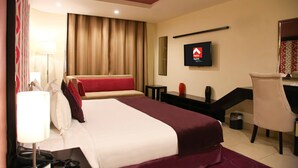 A hotel room with a bed, a desk, a chair, a TV, and a lamp. - Swiss Spirit Hotel & Suites Taif (Taif)