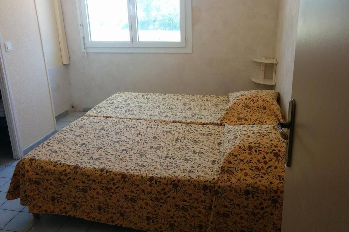 Ein kleines Zimmer mit zwei Betten, einem Fenster und einer Tür.