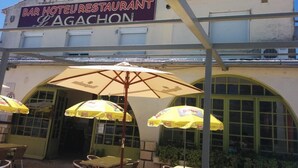 Un établissement proposant un bar, un hôtel et un restaurant, avec une terrasse et des parasols.