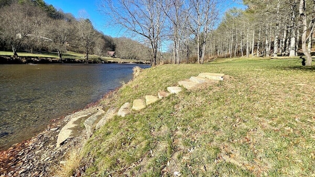 A riverside walkway with stone steps leading to a grassy area, surrounded by trees and a clear blue sky. - Blessed on the New River - Riverfront, WIFI, Small Dog Friendly, Firepit, Gas Grill, Gas Stove (Lansing)