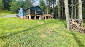 A two-story house with a covered porch and a stone foundation. - Blessed on the New River - Riverfront, WIFI, Small Dog Friendly, Firepit, Gas Grill, Gas Stove (Lansing)