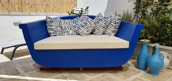 A blue sofa with patterned cushions, a white cushion, and a small table with decorative items. - La Terrazza dell'Antico Gozzo (Monopoli)
