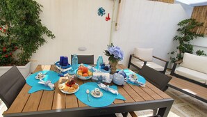 A dining table set with blue placemats, a floral centerpiece, and various dishes and drinks. - La Terrazza dell'Antico Gozzo (Monopoli)