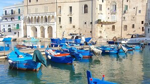 A harbor with boats docked in front of a historic building with arches and balconies. - La Terrazza dell'Antico Gozzo (Monopoli)