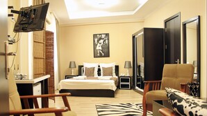 A hotel room with a bed, two chairs, a desk, a TV, and a mirror. - Oriental Hotel (Tbilisi)