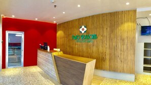 A reception desk with a wooden finish, a red wall, and a logo above it. - Two Seasons Executive Suites (Zamboanga)