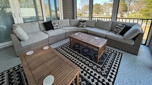 Una sala de estar con un sofá modular, dos mesas de centro de madera y alfombras estampadas.