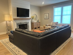 A living room with a fireplace, a television, a sofa, and a window.