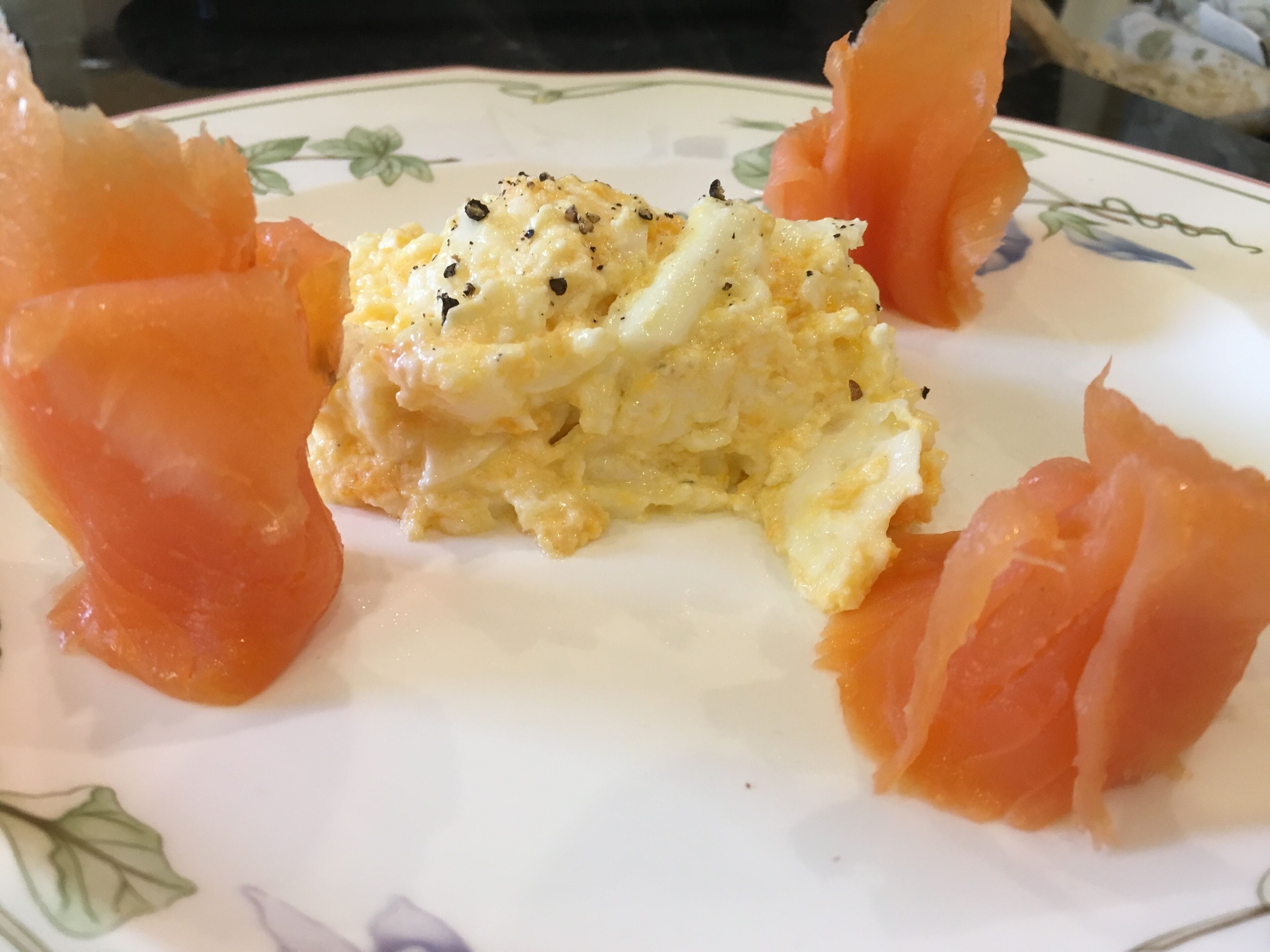 A plate with scrambled eggs and smoked salmon.
