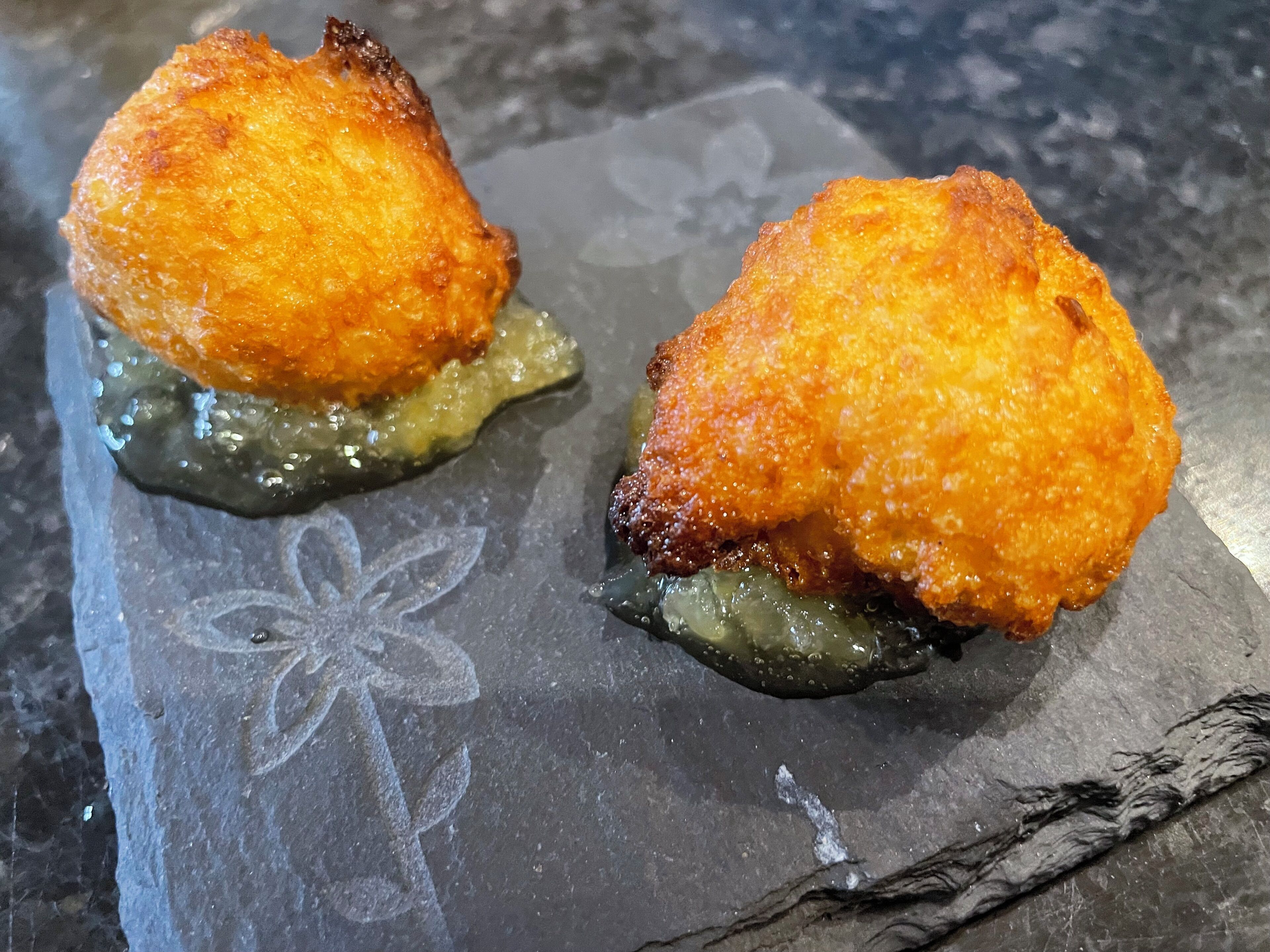 Two fried items on a slate plate with a floral design.