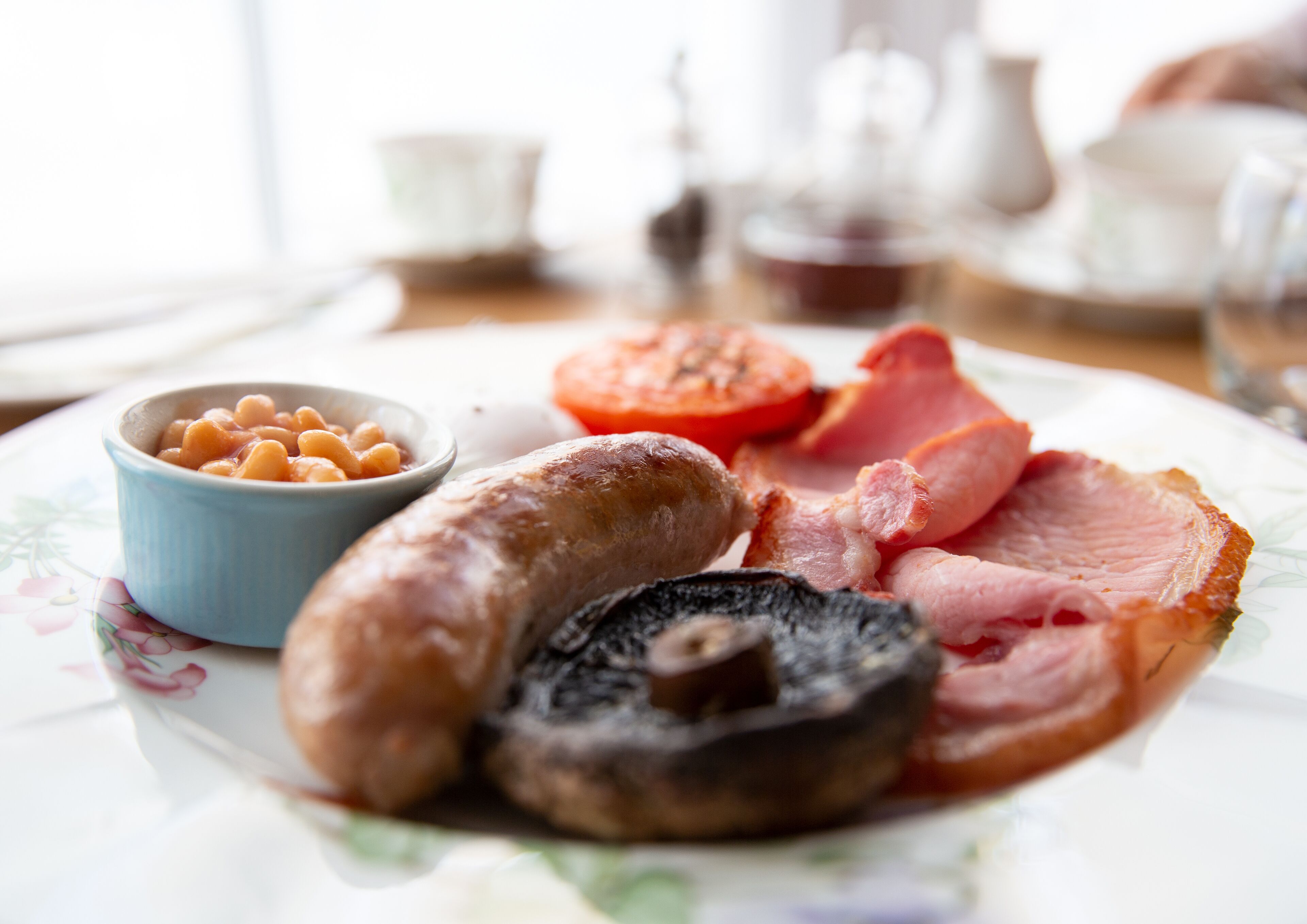 A plate with sausages, bacon, mushrooms, and beans.