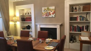 Une salle à manger avec une cheminée, des étagères à livres et une table mise pour le repas.