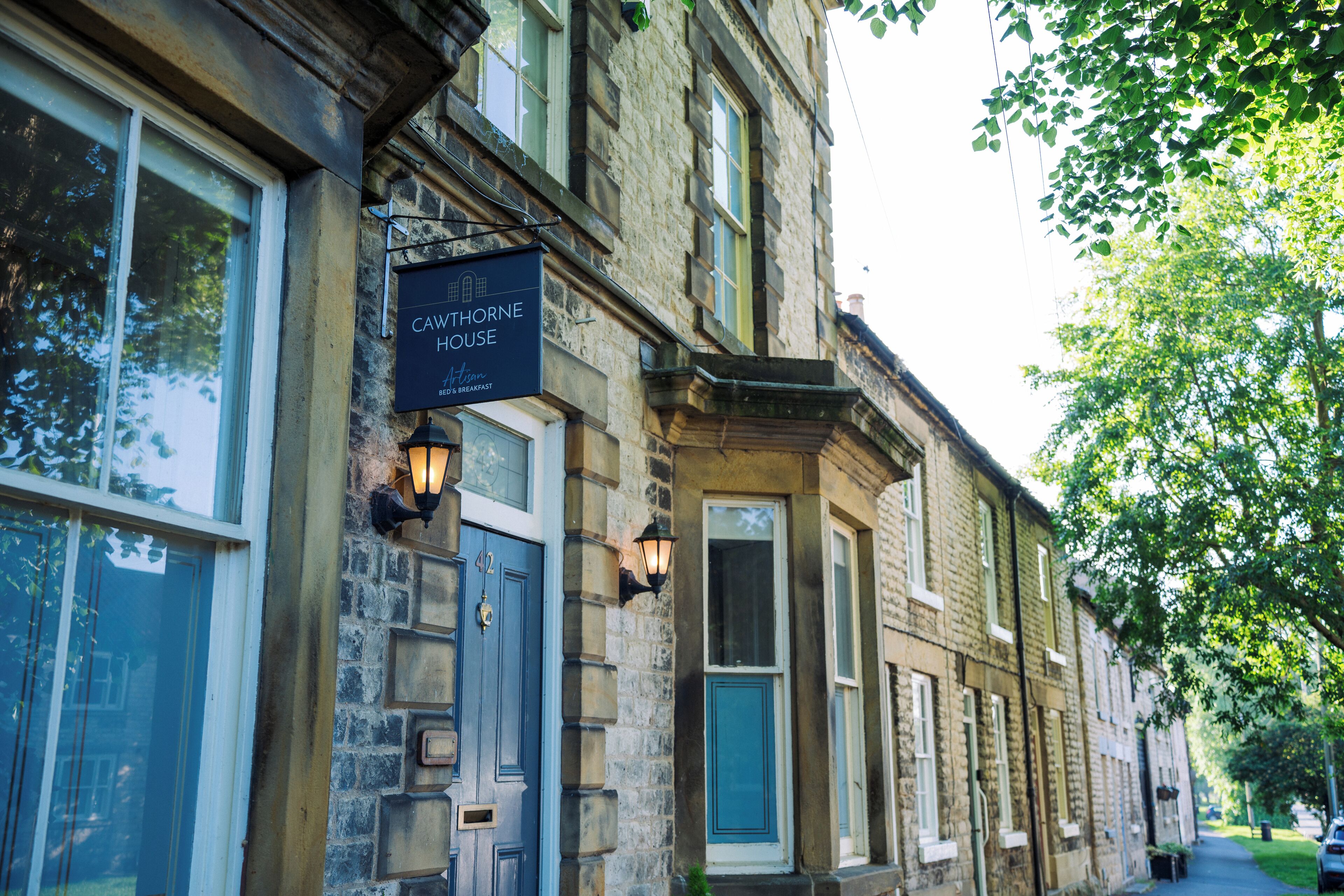 A historic building with a sign reading "CAWTHORNE HOUSE" and a traditional stone facade.