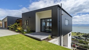 A modern two-story house with a flat roof, large windows, and a small front porch. - Wakatu View - Nelson Luxury Holiday Home (Atawhai)