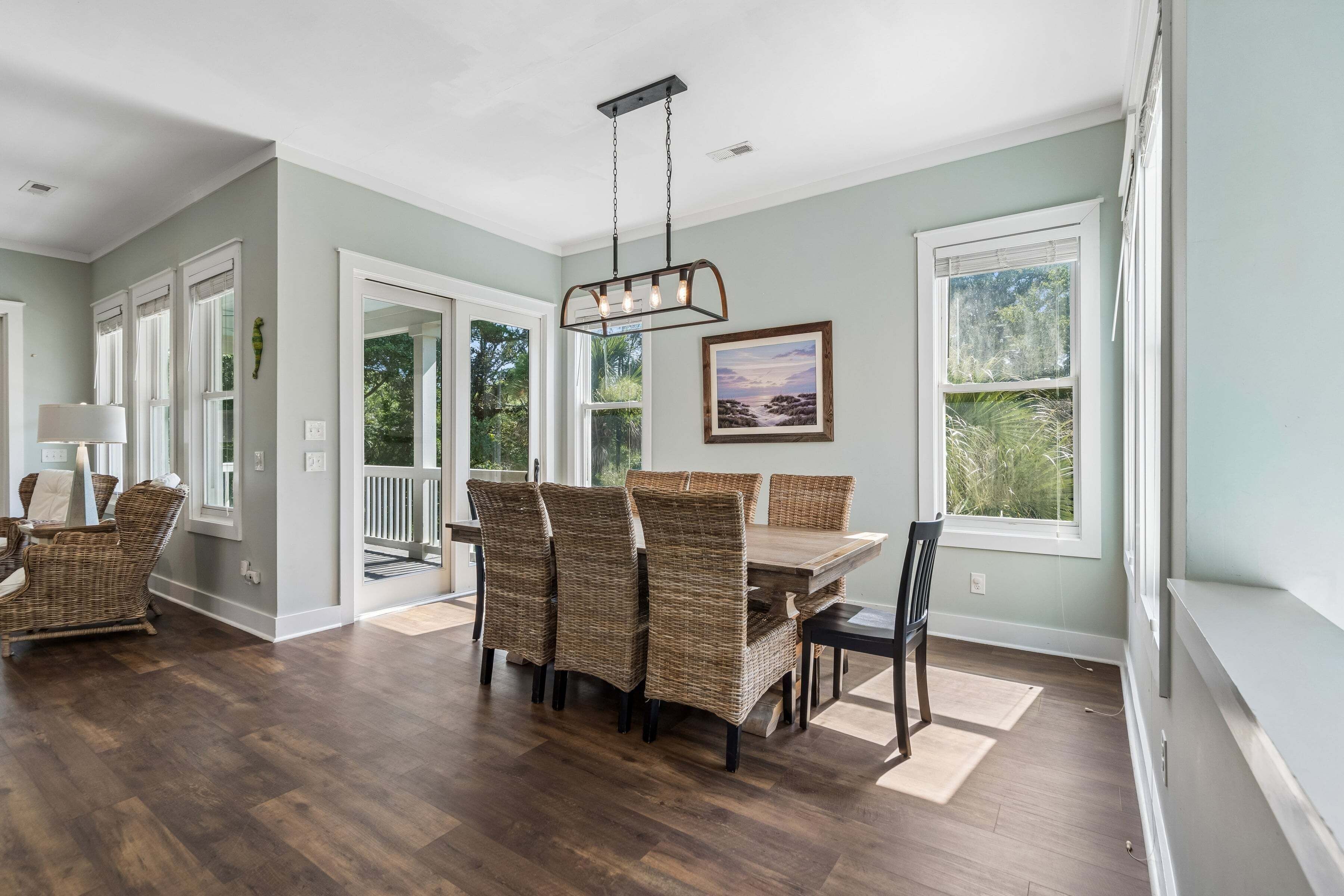 A dining area with a table and chairs, a hanging light fixture, and a window with a view of greenery.