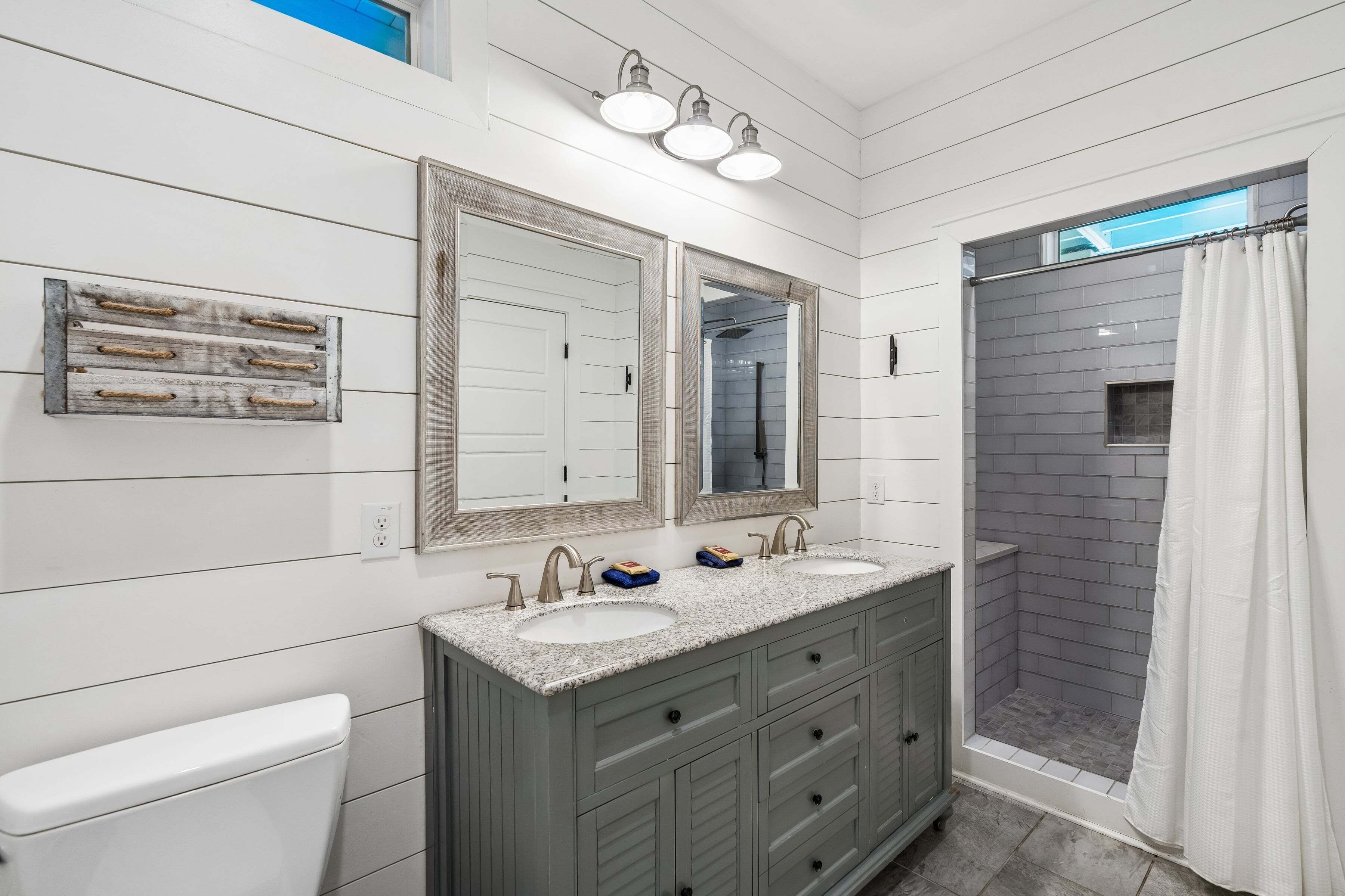 A bathroom with a double sink vanity, a large mirror, and a shower area.