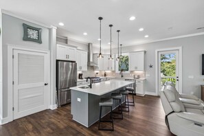 A modern kitchen with a central island, stainless steel appliances, and pendant lighting. - High Tides| Walk to Beach & Center St| Rooftop Deck| Porches| Spacious Living| Seasonal Hot Tub (Folly Beach)