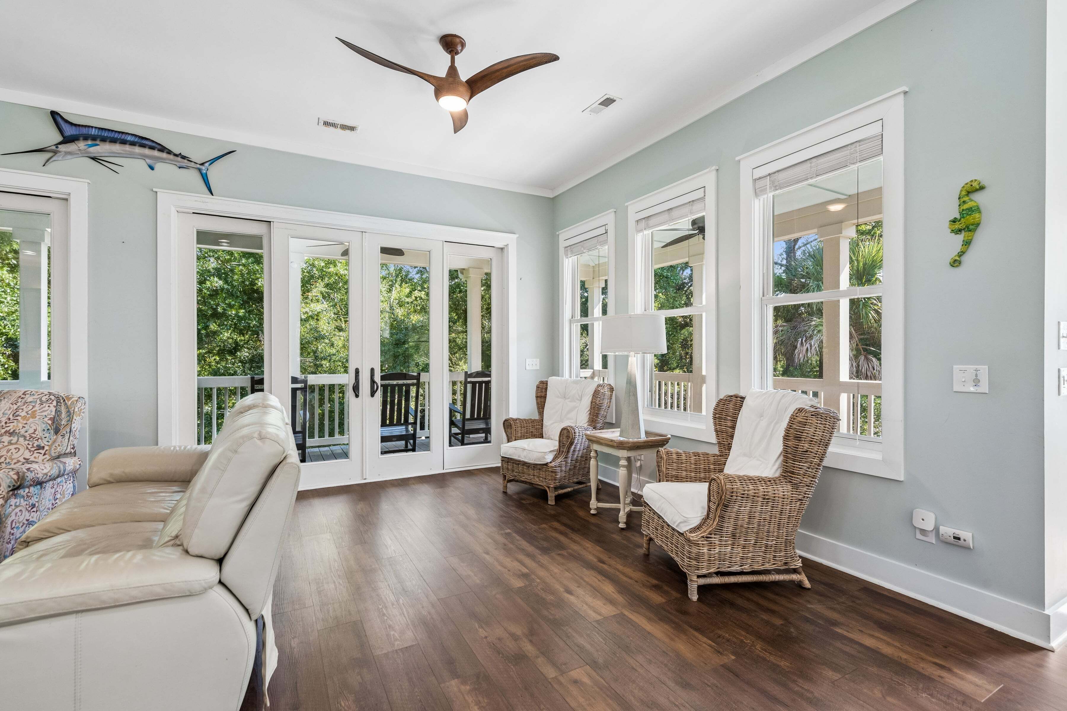 A spacious room with a large window, a ceiling fan, and a wooden floor.