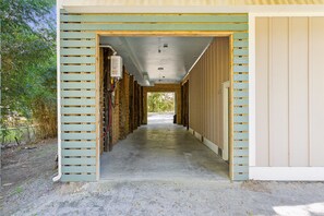 A long, narrow corridor with wooden walls and a concrete floor, leading to a door at the end. - High Tides| Walk to Beach & Center St| Rooftop Deck| Porches| Spacious Living| Seasonal Hot Tub (Folly Beach)
