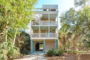 A multi-story building with balconies, surrounded by dense vegetation. - High Tides| Walk to Beach & Center St| Rooftop Deck| Porches| Spacious Living| Seasonal Hot Tub (Folly Beach)