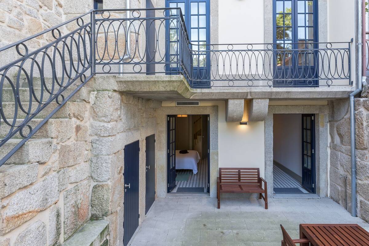 A stone building with a balcony, a wooden bench, and a door leading to a room.