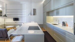 A modern kitchen with a central island, built-in appliances, and a large window. - Casa Amarela (Porto)