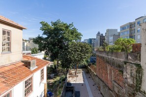 A narrow urban alley with a tree, a small table, and a brick wall.