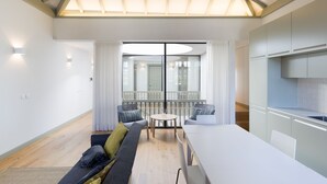 A modern living room with a large window, a dining area, and a kitchen. - Casa Amarela (Porto)