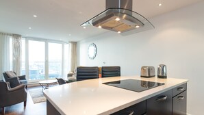 A modern kitchen with a central island, black chairs, and a large window with curtains. - Kenny Apartment  Austin David Apartments (London)