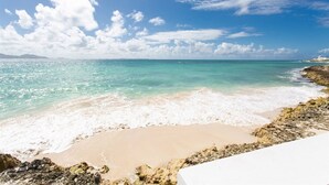 Une plage à l’eau turquoise et limpide, au sable blanc, et parsemée de formations rocheuses.