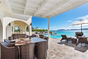 An outdoor seating area with wicker furniture, a pool, and a view of the ocean. - Snapper at Anguillitta (Blowing Point)