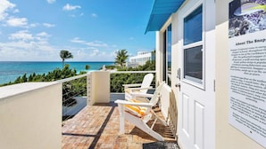 Un balcon avec des chaises blanches et une vue sur l’océan.