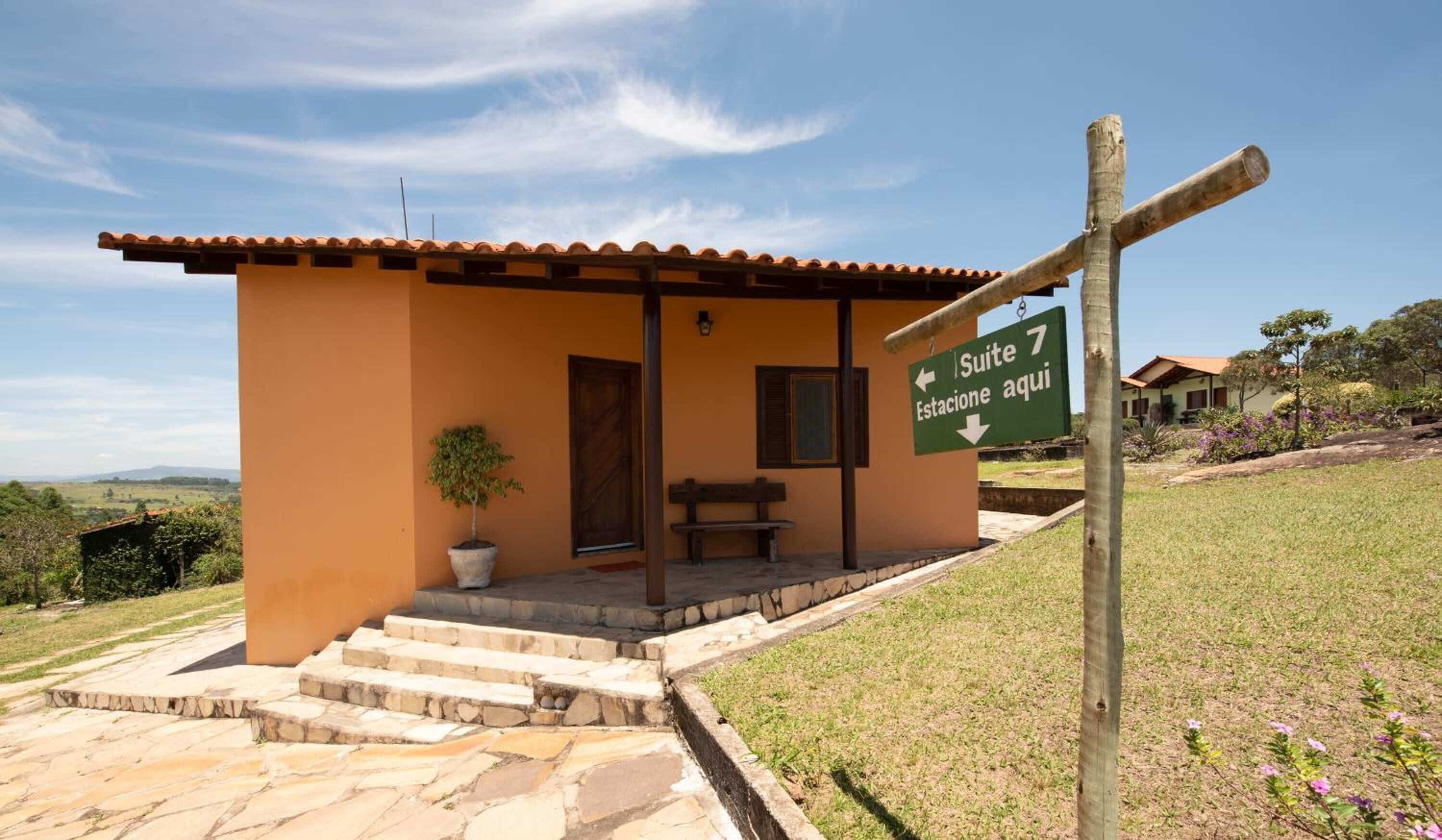 A small building with a tiled roof, a bench, and a sign indicating Suite 7.